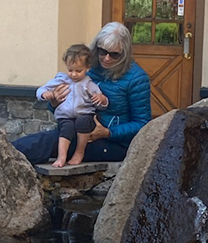 photo of Kelly holding grandson in rocks and water.